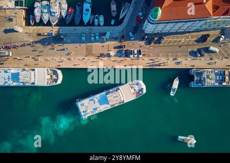 Blick von oben auf Yachten und Boote, die am Yachthafen angedockt sind. Die Fähre legt am Pier an, wo Touristen im Stadtzentrum des Hafens spazieren gehen Stockfoto