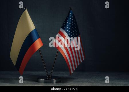 Tischflaggen USA Amerika und Nationalflagge Kolumbien auf dunklem Hintergrund, politisches Konzept Stockfoto