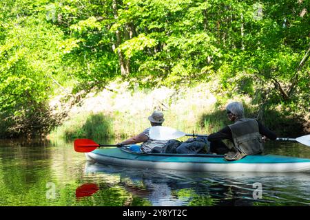 Familien-Kajakausflug für Seigneur und senora. Ein älteres Ehepaar rudert ein Boot auf dem Fluss, eine Wasserwanderung, ein Sommerabenteuer. Altersbezogener Sport, Stockfoto