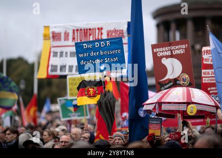 Friedensdemo Nein zu Kriegen DEU, Deutschland, Deutschland, Berlin, 03.10.2024 Demonstranten mit Fahne und Schild die DDR war der bessere Deutsche Staat auf der bundesweiten Demonstration der deutschen Friedensbewegung unter dem Motto Nein zu Kriegen und Hochruestung die Waffen nie Ja zu Frieden und soziale Friedenspolitik in Berlin Deutschland. Der Protest verschiedene Initiativen und Parteien wie Buendnis Bündnis BSW Sahra Wagenknecht , SPD, die linke , Gewerkschaften etc. Fordert einen Waffenstillstand in Gaza und Nahost , Friedensverhandlungen sowie Ende der Sanktionen und den Krieg Ukrain Stockfoto