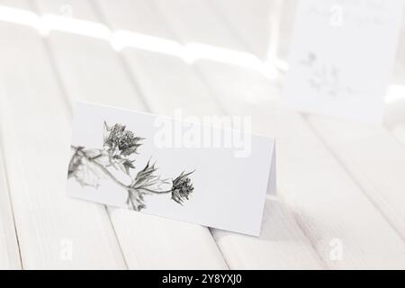 Leere weiße Platzkarte mit einer Schablone für Distelblüten. Eleganter, moderner Hochzeitsempfang Stockfoto