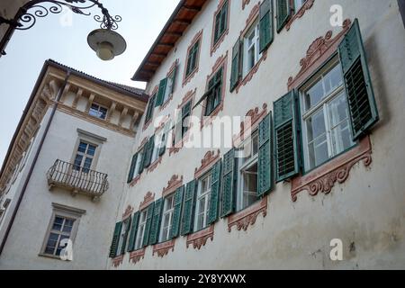 Ein Gebäude mit alten grünen Fensterläden und braunen Stuckfenstern, Meran, Norditalien. Stockfoto