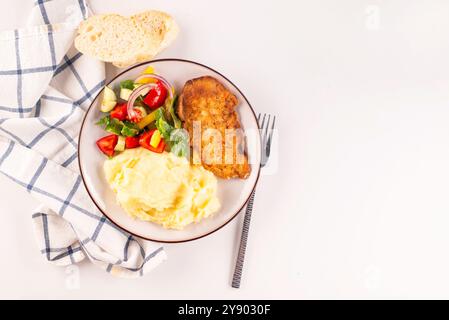 Gebratenes Hähnchensteak oder Schnitzel mit Kartoffelpüree und Gemüsesalat auf einem Teller auf weißem Tisch Stockfoto