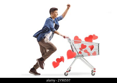Profilaufnahme eines glücklichen jungen Mannes, der mit roten Herzen in einem Einkaufswagen auf weißem Hintergrund läuft Stockfoto