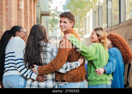 Eine Gruppe von Studenten läuft auf dem Universitätscampus, während einer von ihnen zurückkehrt und lächelnd in die Kamera schaut. Multirassische Teenager-Freunde auf der Highschool gehen in die Klasse, um zusammen zu lernen. Hochwertige Fotos Stockfoto