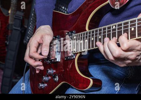 Dies ist ein Nahaufnahme-Bild einer Person, die geschickt eine elektrische Gitarre spielt, ihre Hände und die Details des verwendeten Instruments zeigt Stockfoto