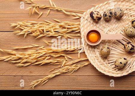 Weidenmatte in Form von Blatt mit frischen Wachteleiern und Weizen auf hölzernem Hintergrund Stockfoto