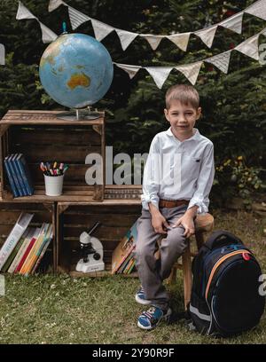 Ein Schuljunge steht in der Nähe eines Globus und Schulbedarf. Ein Erstklässler. Der Junge geht zur Schule. Hochwertige Fotos Stockfoto