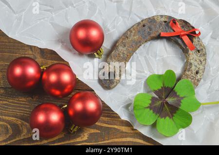 Hufeisen, Glücksklee und rote Weihnachtskugeln Stockfoto