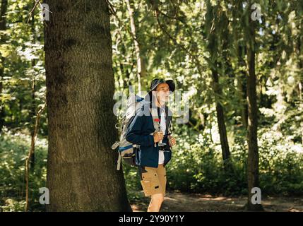 Senior Mann mit Rucksack und Wanderkleidung, der im Wald spaziert. Reifer Mann genießt die Aussicht während eines Spaziergangs im Wald. Senior-Mann mit Rucksack und hik Stockfoto