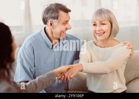 Glückliches älteres Paar, das weiblichen Arzt Handschlag gibt Stockfoto