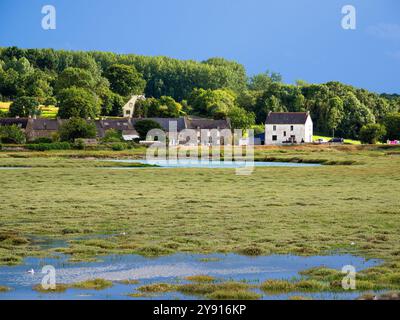 Dinan, Frankreich - 19. Juli 2024: Ein malerischer Blick auf eine ländliche Landschaft in der Bretagne mit einer Ansammlung traditioneller Steinhäuser in der Nähe eines ruhigen Wasserkörpers. Stockfoto