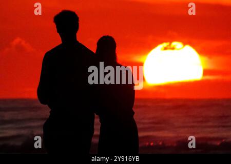 Isle Of Palms, Usa. Oktober 2024. Ein Paar, umgeben vom Sonnenaufgang, hält am Strand des Wild Dunes Resort, 7. Oktober 2024 in Isle of Palms, South Carolina. Quelle: Richard Ellis/Richard Ellis/Alamy Live News Stockfoto