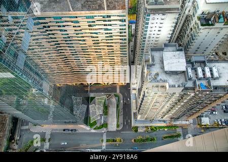 Fast senkrechte Aussicht, hängt über einem Balkon der Wohnung, hoch oben im Gebäude, Sonnenuntergangslicht reflektiert von der modernen Stadtarchitektur und den urbanen en en Stockfoto