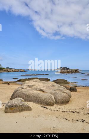 Plage de Tourony, Tournoy Beach, Cote de Granit Rose, Bretagne, Frankreich, leichter Sand und Badegäste am Strand bei ruhigem Wetter. Runde Granitfelsen mit Stockfoto