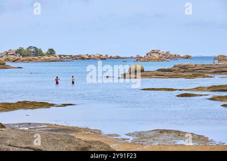 Plage de Tourony, Tournoy Beach, Cote de Granit Rose, Bretagne, Frankreich, heller Sand und Badegäste am Strand bei ruhigem Wetter. Runder Granit r Stockfoto