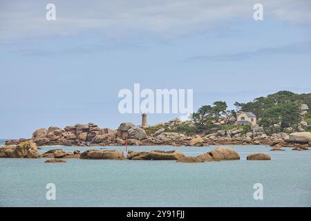 Leuchtturmfarbener Sand und runde Granitfelsen mit Blick über blaues Wasser zum Leuchtturm Phare de Ploumanac'h, Plage de Tourony, Tournoy Beach, Stockfoto