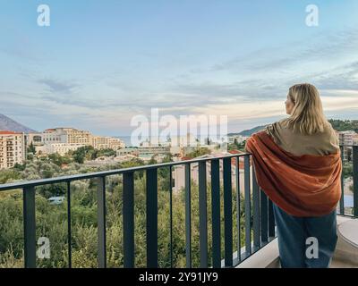 Eine Frau, die auf dem Balkon steht, während der Sommersonnenuntergang in Montenegro liegt Stockfoto