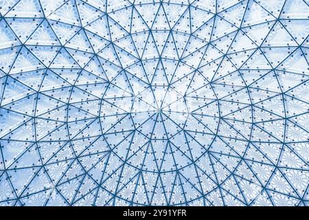 Architektonische Glasstruktur mit geometrischem Dreiecksmuster auf blauem Himmel. Stahlglasdach des Gebäudes, durchsichtiges Dachfenster Stockfoto