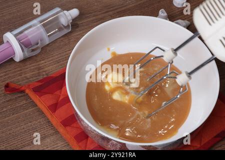 Verfahren zur Herstellung von Karamellcreme. Karamell, Eiweiß und Butter mit Mixer schlagen. Backen zu Hause. Nahaufnahme. Stockfoto