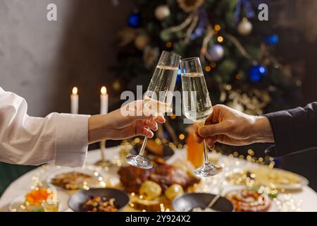 Hände mit Sektgläsern Nahaufnahme auf dem Hintergrund eines festlichen Weihnachtstisches, Concept christmas Stockfoto
