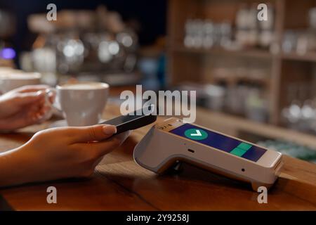 Der Kunde macht kontaktlose NFC-Zahlung per Telefon über das Terminal im Café, Konzept erfolgreiche Zahlung, elektronische Geldbörse Stockfoto