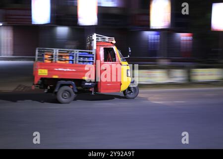 Eine Auto-Rikscha, die Kisten auf einer ruhigen Nachtstraße trägt, zeigt ihre Nutzbarkeit als Gütertransportfahrzeug Stockfoto