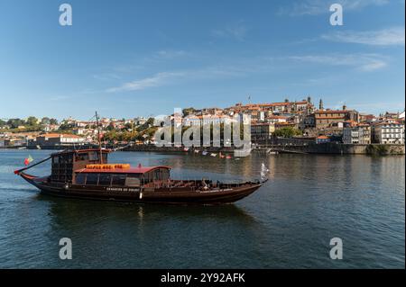 Porto, Portugal - 12. September 2024 : Ein traditionelles Boot gleitet entlang des Flusses und zeigt die Schönheit der Architektur von Porto. Stockfoto