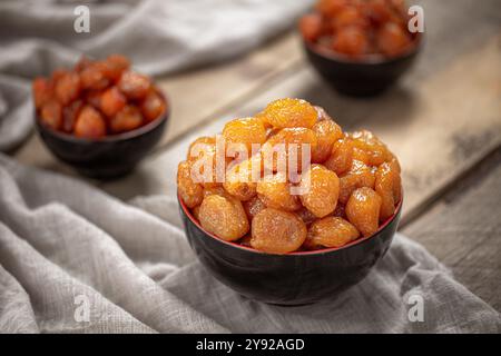 Nahaufnahme kandierter getrockneter Aprikosen in schwarzen Schüsseln, perfekt für gesundes Naschen oder als natürliche, lebendige Dessertoption Stockfoto