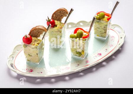 Eleganter Kartoffelsalat in Glasbechern, garniert mit Oliven, Brot und Kirschtomaten, serviert auf einem dekorativen Tablett Stockfoto