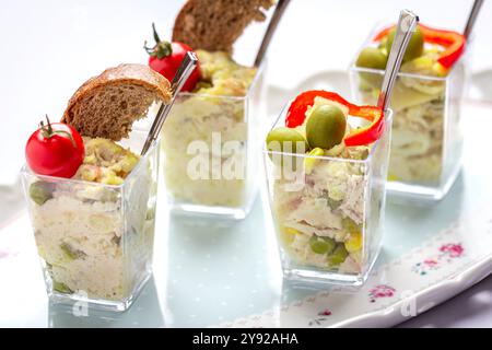 Mini-Hähnchensalatbecher mit Kirschtomaten, Oliven und Vollkornbrotscheibe, serviert in Gläsern, ideal für Partyvorspeisen Stockfoto