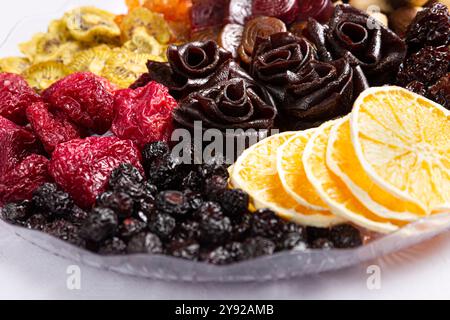 Eine Nahaufnahme von verschiedenen getrockneten Früchten und Nüssen, einschließlich Kiwi, Aprikose und künstlerischen rosenförmigen Fruchtbrötchen, wunderschön angeordnet. Stockfoto