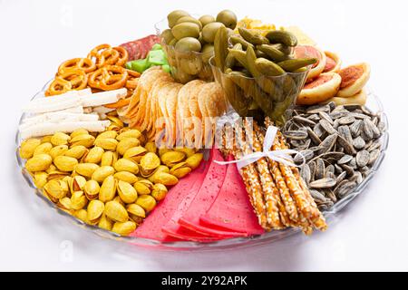 Köstliche Snacktafel mit einer Mischung aus Oliven, Brezeln, Chips, Salami, Brotstangen, Pistazien, Gurken und Nachos, ideal für Unterhaltung Stockfoto