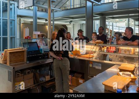 Porto, Portugal - 12. September 2024 : Ein Anbieter spricht an einem lebhaften Marktstand mit einer Menge von Kunden zusammen. Stockfoto