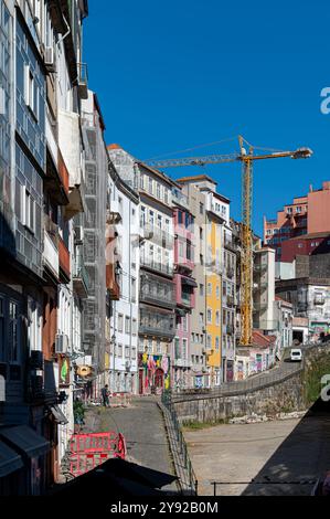 Porto, Portugal - 12. September 2024 : pulsierende Gebäude säumen eine Porto-Straße mit Kränen im Hintergrund. Stockfoto