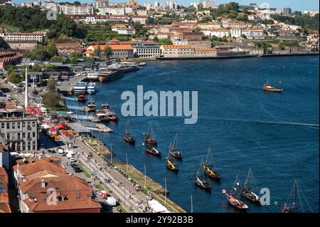 Porto, Portugal - 13. September 2024 : lebhafter Blick auf den Fluss mit traditionellen Booten, die entlang des Ufers in einer belebten Stadt angedockt werden Stockfoto