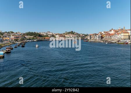 Porto, Portugal - 13. September 2024 : Boote fahren auf dem Fluss Douro mit dem lebhaften Porto im Hintergrund an einem sonnigen Tag Stockfoto