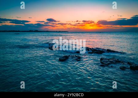 Wunderschöner Blick auf die Drohnen, die auf schwarze vulkanische Felsen vor der Küste von Grand Baie, Mauritius, prallen, mit einem atemberaubenden Sonnenuntergang im Hintergrund Stockfoto