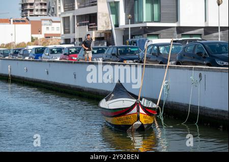 Aveiro, Portugal - 11. September 2024 : Ein Mann steht in der Nähe einer Reihe von Fahrzeugen, während ein Boot am Ufer angedockt wird. Stockfoto