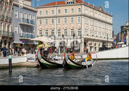 Aveiro, Portugal - 11. September 2024 : traditionelle Boote, die tagsüber in einer belebten portugiesischen Stadt an der Uferpromenade aufgereiht sind. Stockfoto