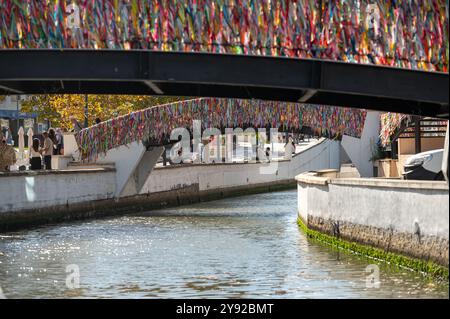 Aveiro, Portugal - 11. September 2024 : farbenfrohe Bänder hängen an Brücken über einem friedlichen Wasserweg in einer städtischen Umgebung. Stockfoto