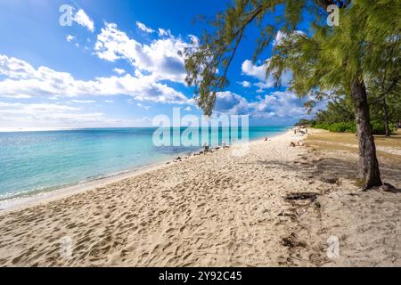 Malerischer Blick auf den schönen und sauberen Strand von Le Morne, Mauritius, mit nur wenigen Leuten, die vor dem türkisfarbenen Wasser am Riff sonnen Stockfoto