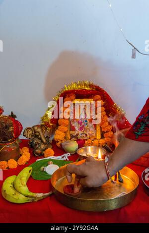 Eine brennende Schlammlampe (diya), umgeben von leuchtenden Blumen während Navratri, einem Hindu-Festival zu Ehren indischer Göttinnen. Gefangen genommen in Uttarakhand, Indien. Stockfoto