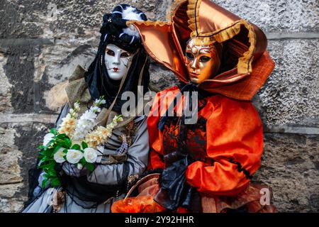 Auffällige, lebendige Farben der Masken und exotischen Kostüme, die von zwei Teilnehmern des jährlichen venezianischen Karnevals in Annecy, Frankreich, öffentlich präsentiert werden Stockfoto