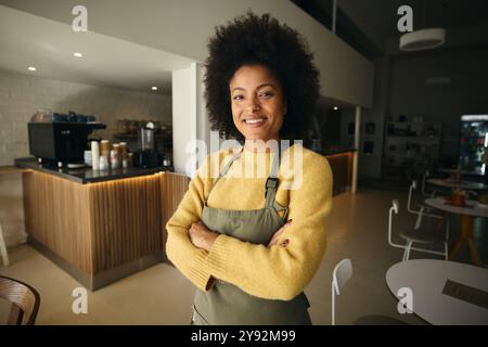 Eine afrikanische Kellnerin steht mit überkreuzten Armen Stockfoto