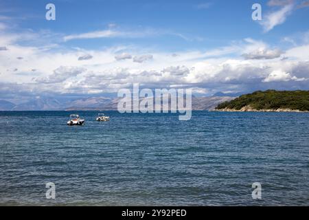 Blaues Wasser des Ionischen Meeres im Nordosten der Insel. Berge in Albanien am Horizont. Blauer Himmel mit weißen Wolken. Agios Spyridon, Co Stockfoto