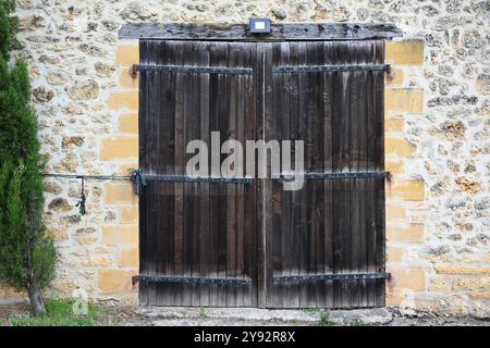Alte hölzerne Scheunentüren umgeben von einer Kalksteinmauer Stockfoto