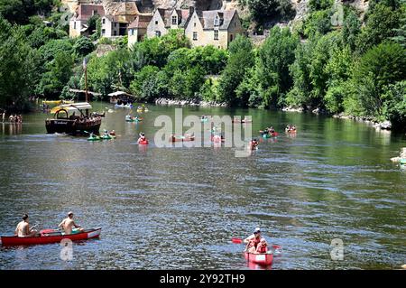 La Roque Gageac, Frankreich; 24. juli 2024: Kanufahrer und ein touristisches Gabarrenboot auf der Dordogne bei La Roque Gageac in Frankreich Stockfoto