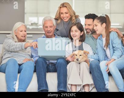 Große Familie, Lächeln und entspannen Sie mit Laptop auf Sofa für Internet, Verbindung und Film zusammen. Eltern, Großeltern und Kinder mit Hund Stockfoto
