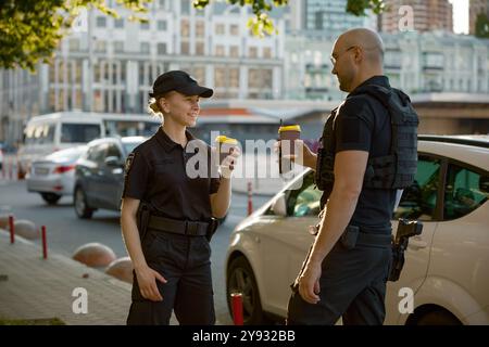 Verschiedene junge Polizisten trinken Kaffee und genießen Pausen Stockfoto